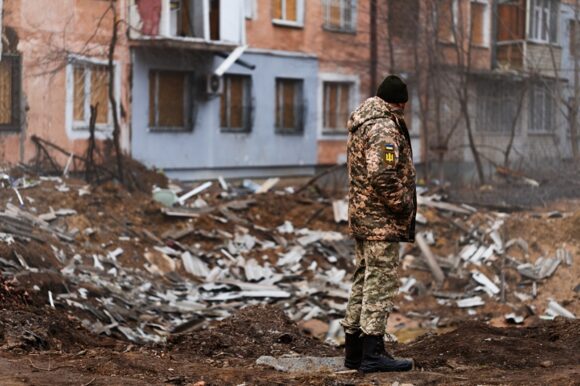A Ukrainian serviceman stands next to the shelling of a civilian building in Kherson by the Russian Office block and residential buildings hit by missiles – 21 civilians dead (3 children)